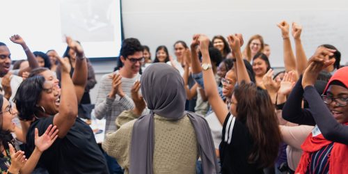 group of students with arms in the air cheering and smiling